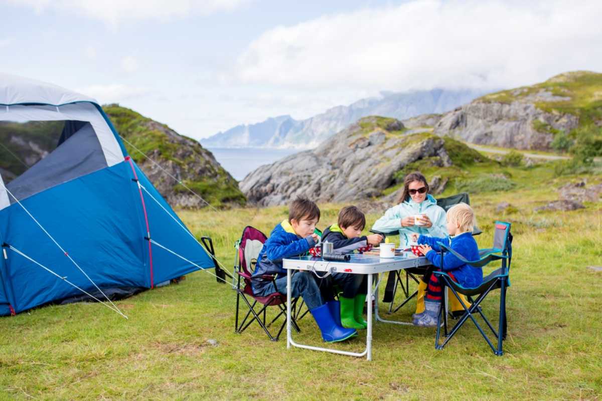 Family camping beside a tent with mountain and coastal views.