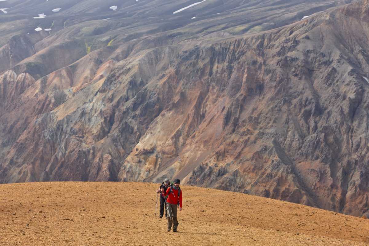 Hikers crossing colorful mountain terrain in Iceland’s Highlands.