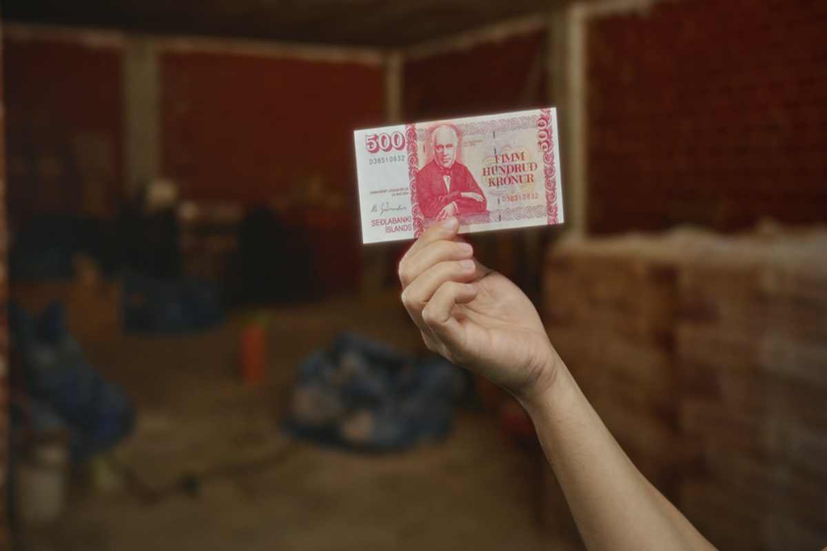 Traveler holding a 500 Icelandic króna banknote while planning an Iceland trip budget.