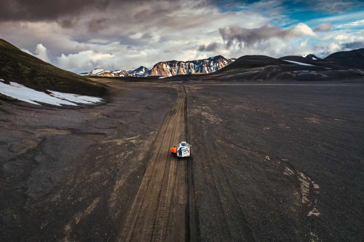 4x4-Fahrzeug, das über eine abgelegene schwarze Sandstraße im isländischen Hochland fährt.