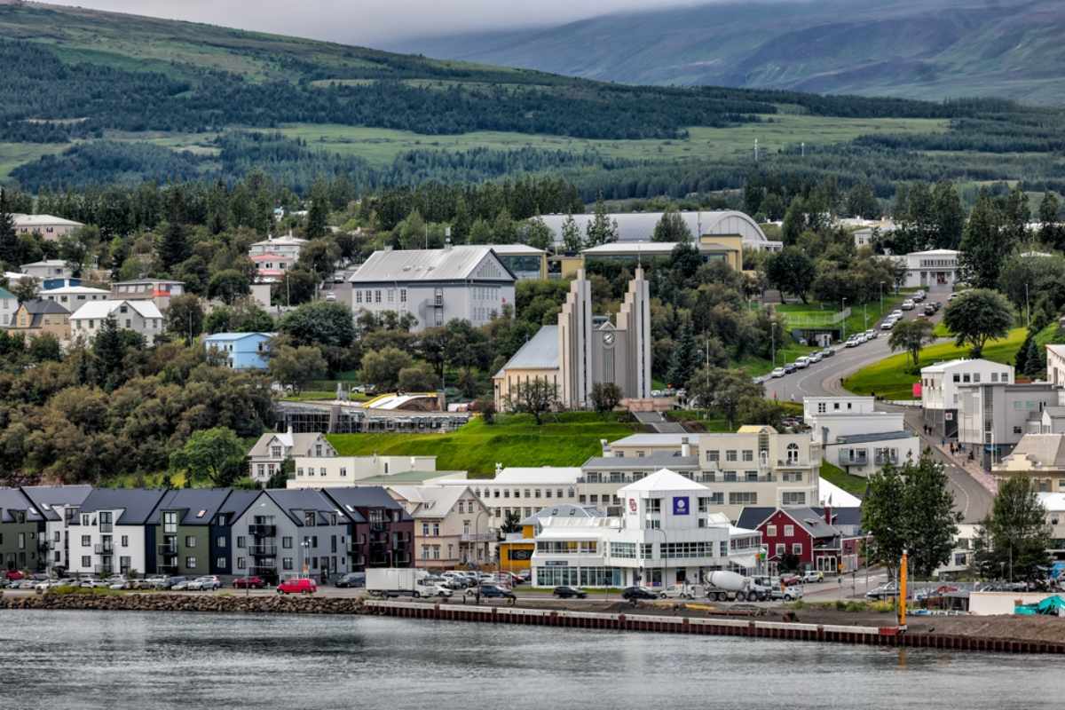 Blick auf Akureyri mit seiner Kirche, dem Hafen und grünen Bergen im Hintergrund.