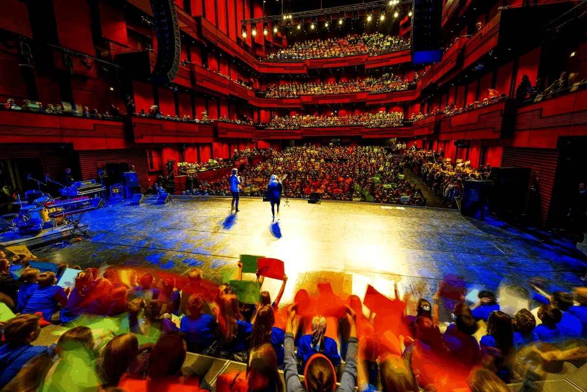 Audience fills a red Reykjavik concert hall as performers stand on stage, showcasing Iceland’s lively April festivals and cultural scene