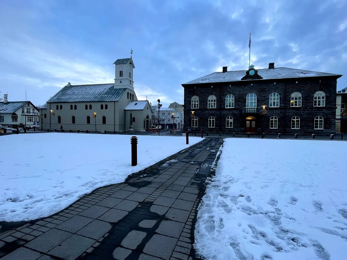 Snow-covered Austurvöllur square in Reykjavík with the Cathedral and Icelandic Parliament, offering winter tips for visiting Iceland in February