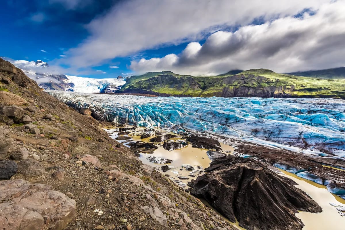 Blue Iceland glacier with crevassed ice, black moraine and rugged mountains, highlighting Jökulsárlón Glacier Lagoon adventures