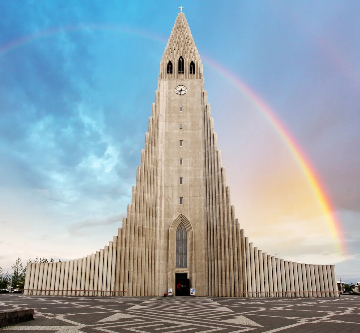 Hallgrímskirkja church rises over Reykjavik with a vivid rainbow and patterned plaza, an iconic landmark among Iceland capital sights