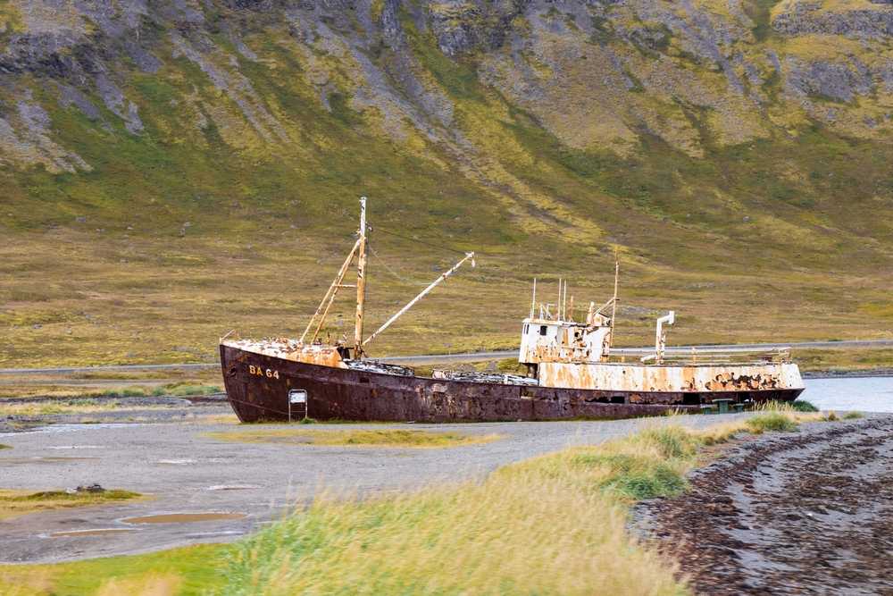 Rusting Gardar BA 64 shipwreck on a remote Icelandic fjord shore, backed by mossy mountains and wild coastal scenery in November