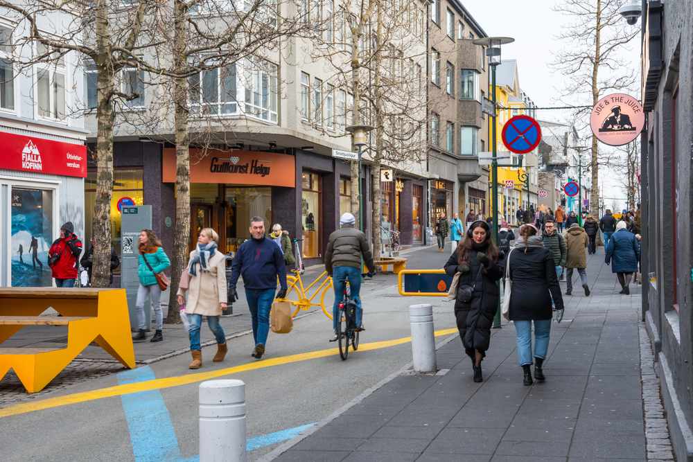 Pedestrians and cyclists on Reykjavik's Laugavegur shopping street in November, with boutiques, cafes and winter city life in Iceland