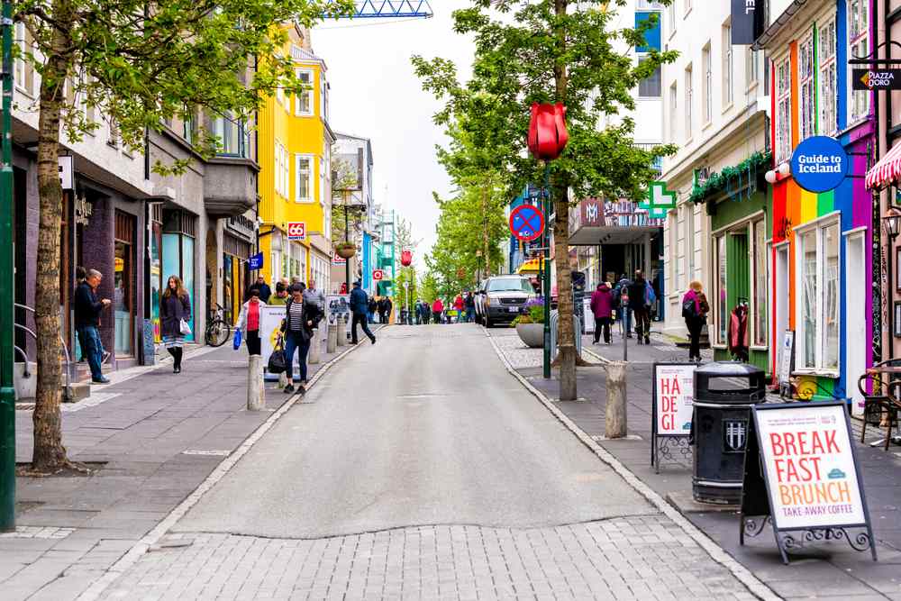 Colorful downtown Reykjavik street with shops, cafes, pedestrians and trees, highlighting city walks and local culture in November Iceland