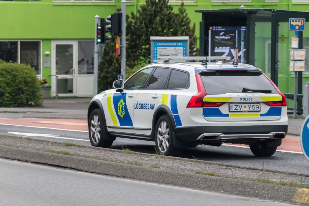 Icelandic police Volvo SUV parked on a Reykjavik street beside a bus stop, illustrating public safety and travel security in Iceland