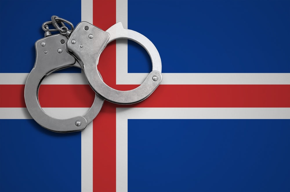 Metal handcuffs resting on the Icelandic flag, symbolizing crime, law enforcement and traveler safety concerns for visitors in Iceland