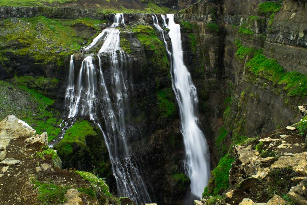 Glymur waterfall splits into multiple cascades over moss-covered basalt cliffs, plunging into a dramatic canyon in West Iceland.