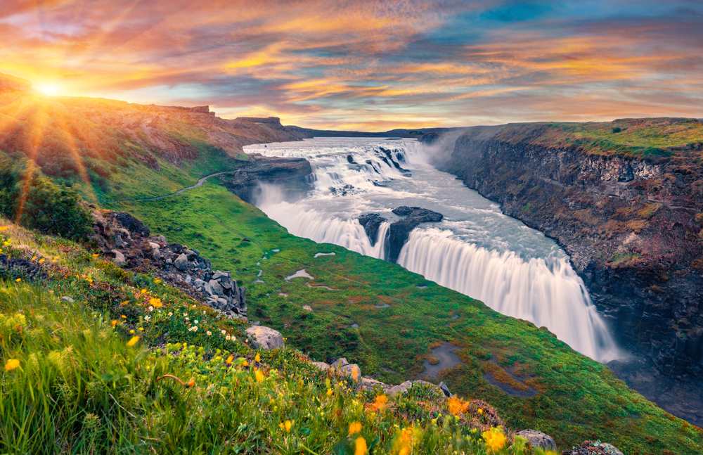 Golden sunset over Gullfoss waterfall as powerful glacial water cascades through a rugged green canyon on Iceland’s Golden Circle route.