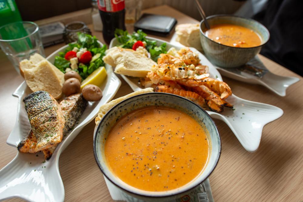 Seafood meal with grilled salmon, lobster tails, salad, bread and creamy soup, illustrating restaurant and food costs during a trip to Iceland.