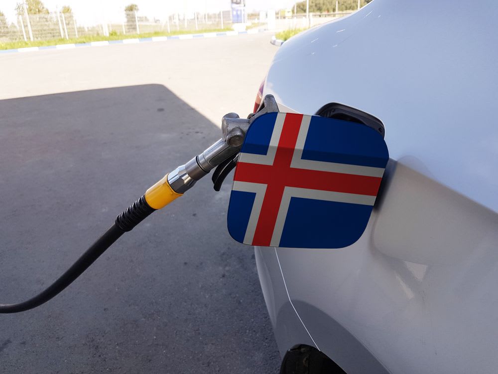 Fuel nozzle filling a car with an Icelandic flag on the fuel door, illustrating petrol prices and driving costs for an Iceland road trip.