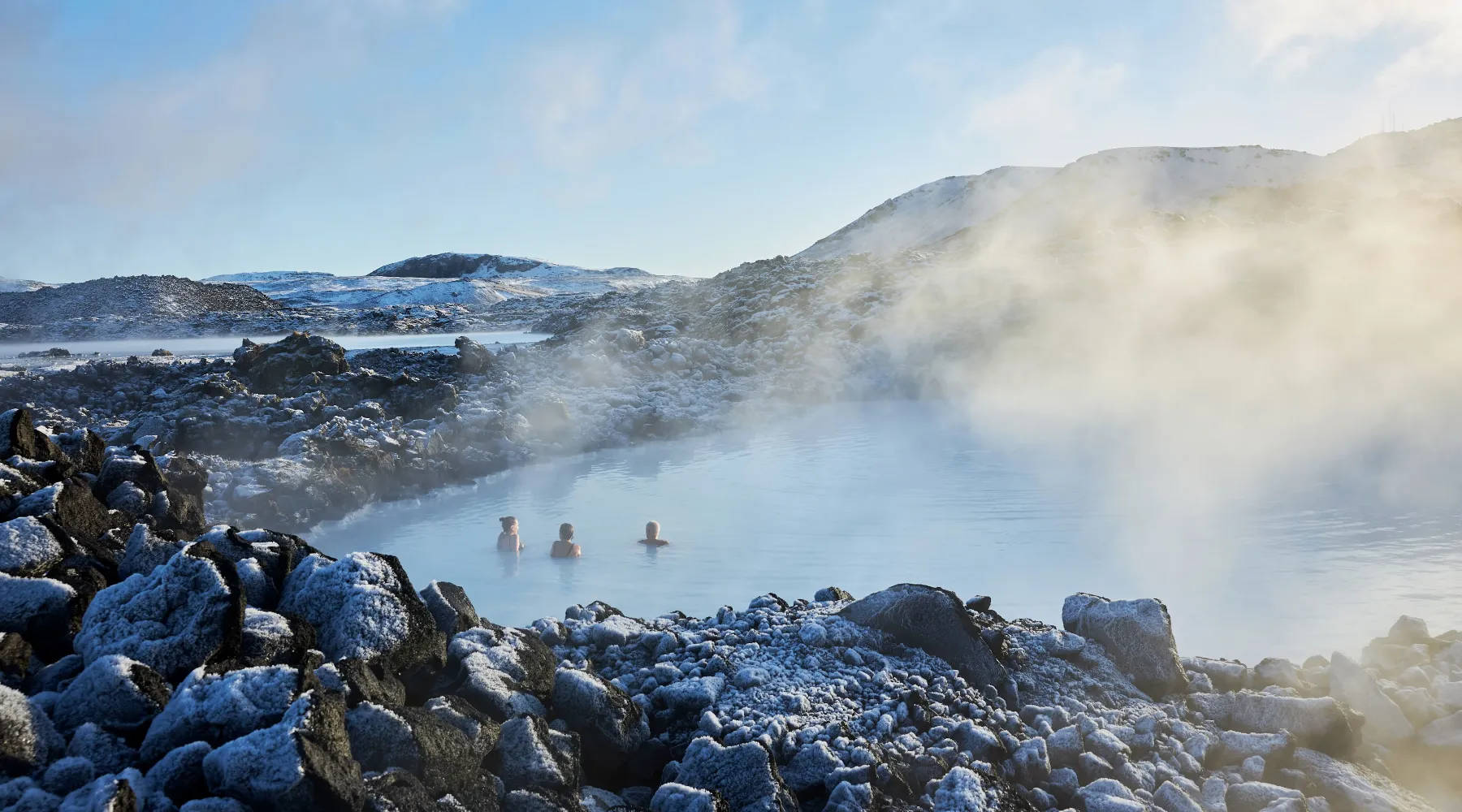 Panoramic view of the Blue Lagoon in Iceland with steam rising from the lagoon's blue-tinted waters.