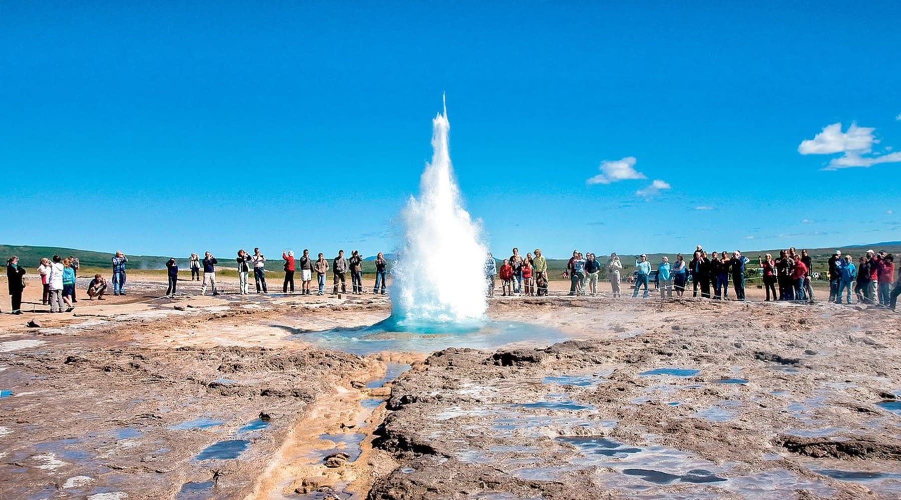 Geysir erupting in front of a group of tourists on the Golden Circle.