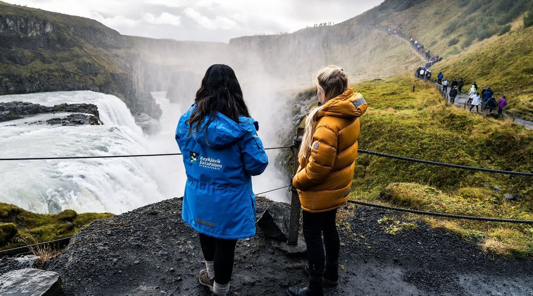 A couple of tourists watching the impressive Gullfoss waterfall up close.