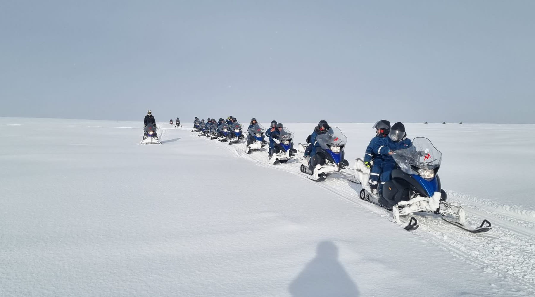 Reihen von Schneemobilen mit Touristen, die bereit für die Tour sind.