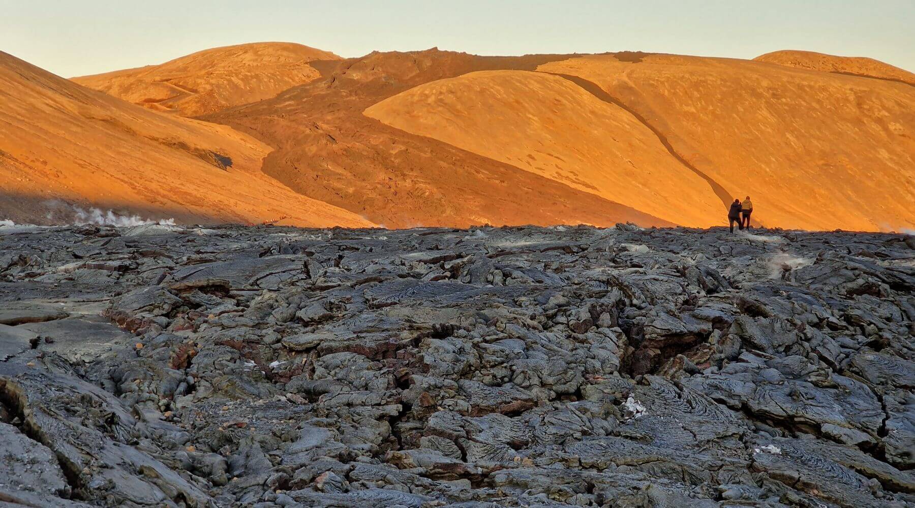Vast lava field contrasting with the brown mountains of the Icelandic landscape.