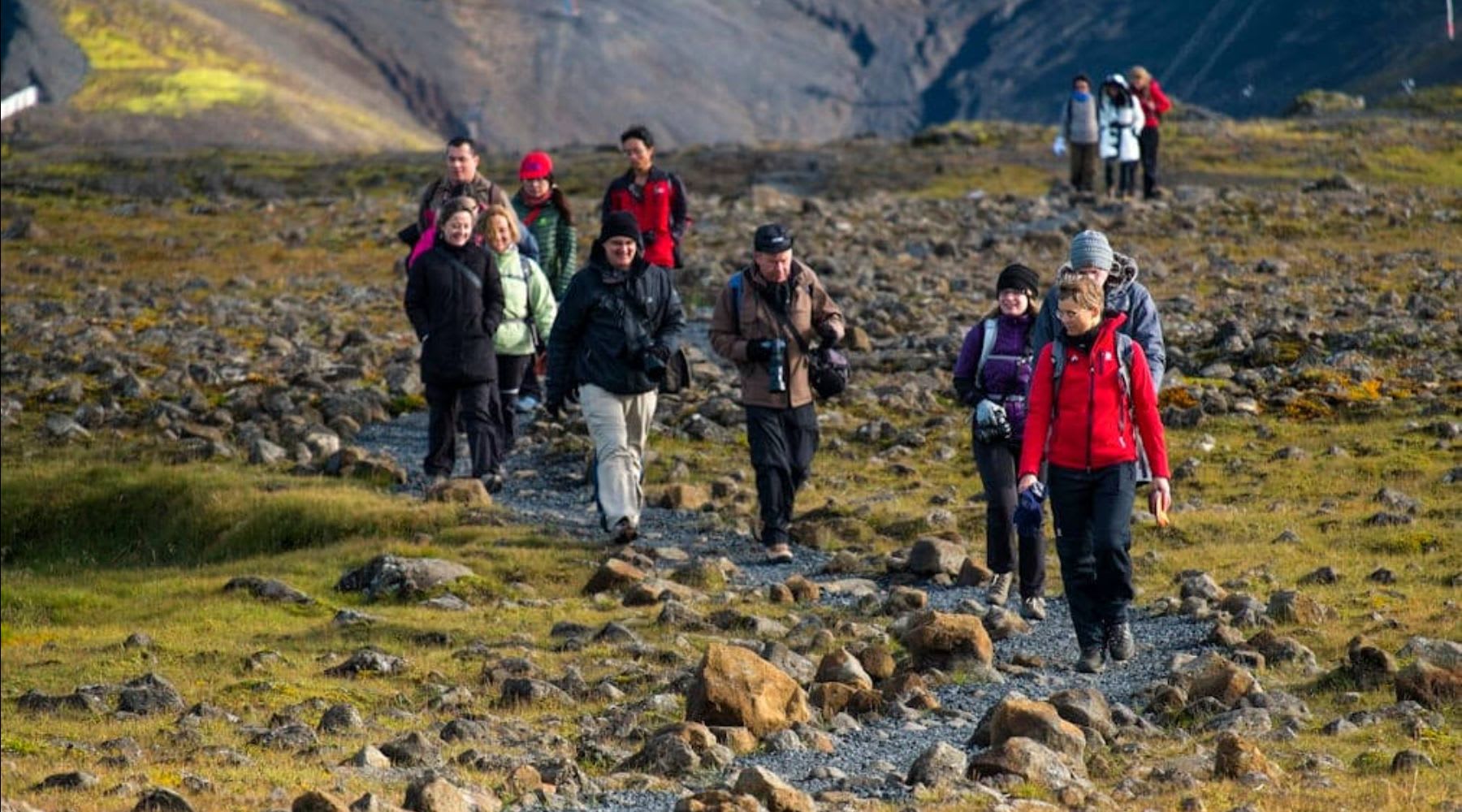 Group of travelers hiking through a rocky volcanic landscape in Iceland