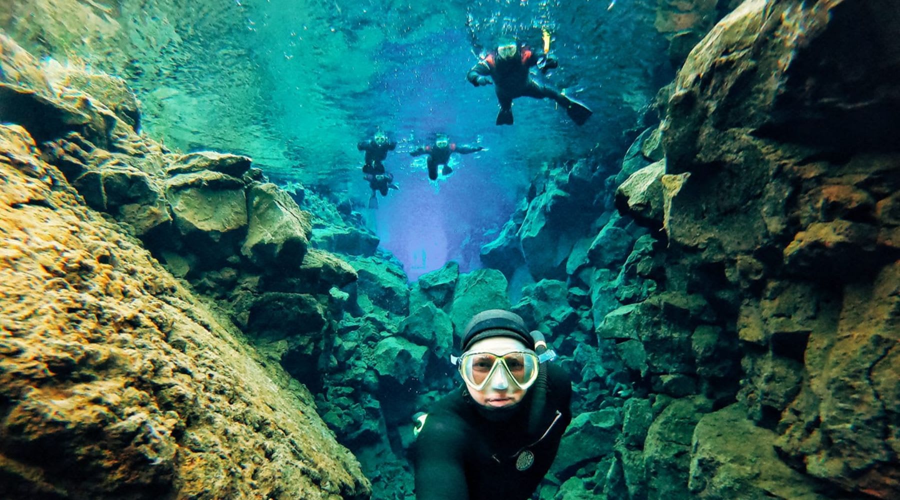 Group of snorkelers exploring the underwater rock formations of Silfra