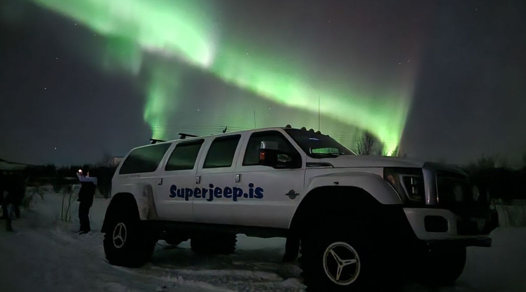 Super Jeep garé sous de vives aurores boréales vertes en Islande
