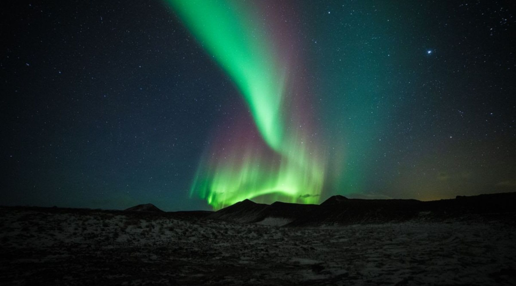 Intensa aurora boreal verde sobre un paisaje nevado de Islandia por la noche