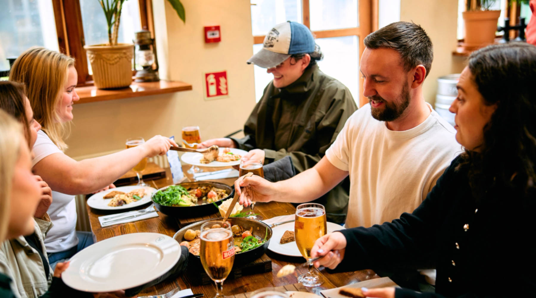 Eine Gruppe von Menschen, die gemeinsam isländisches Essen an einem Gemeinschaftstisch essen.