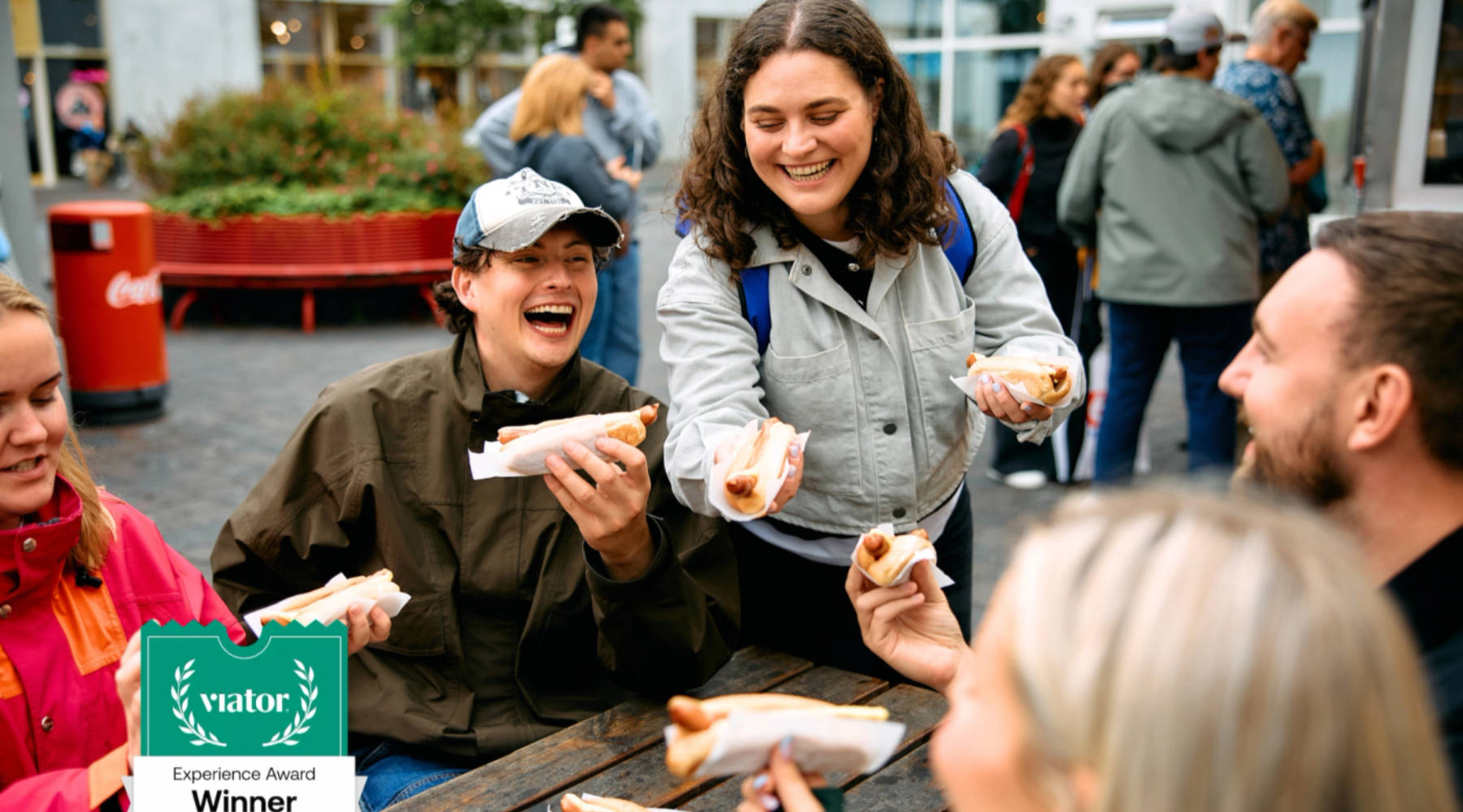 Eine Gruppe von Menschen, die isländische Hot Dogs essen, lacht und hat Spaß.
