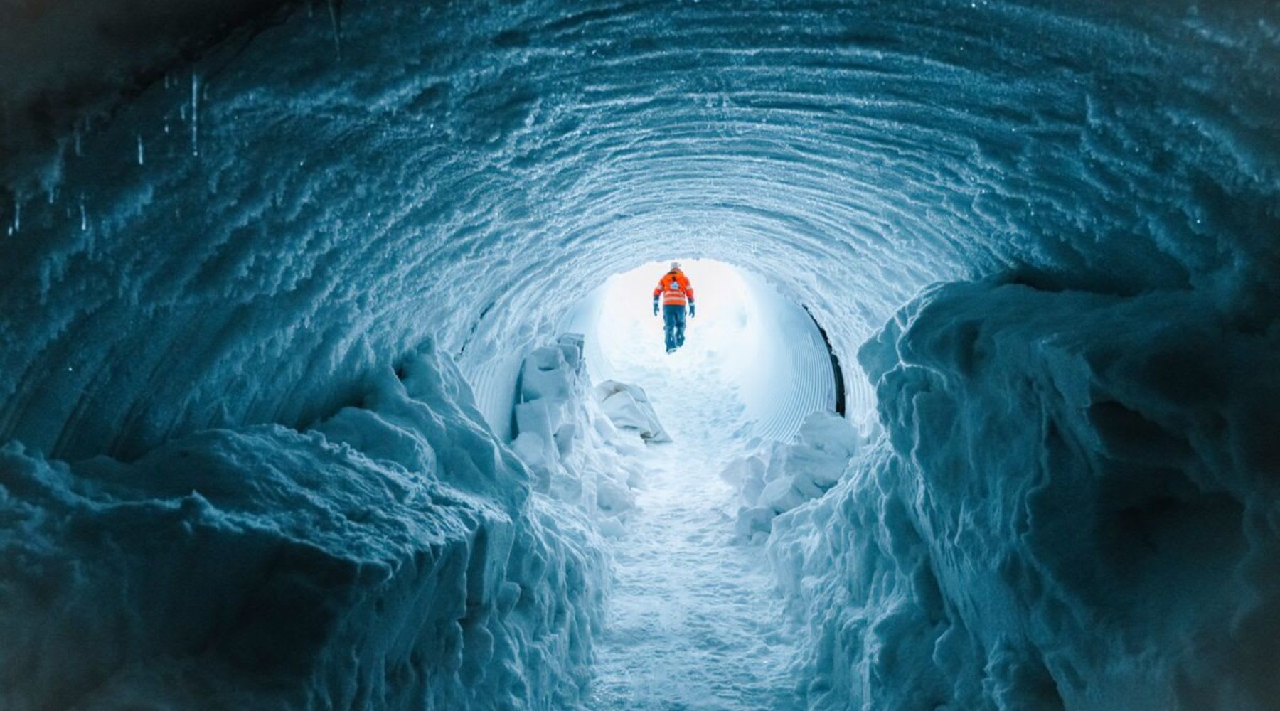 Eishöhle mit einem Mann in Orange im Hintergrund.