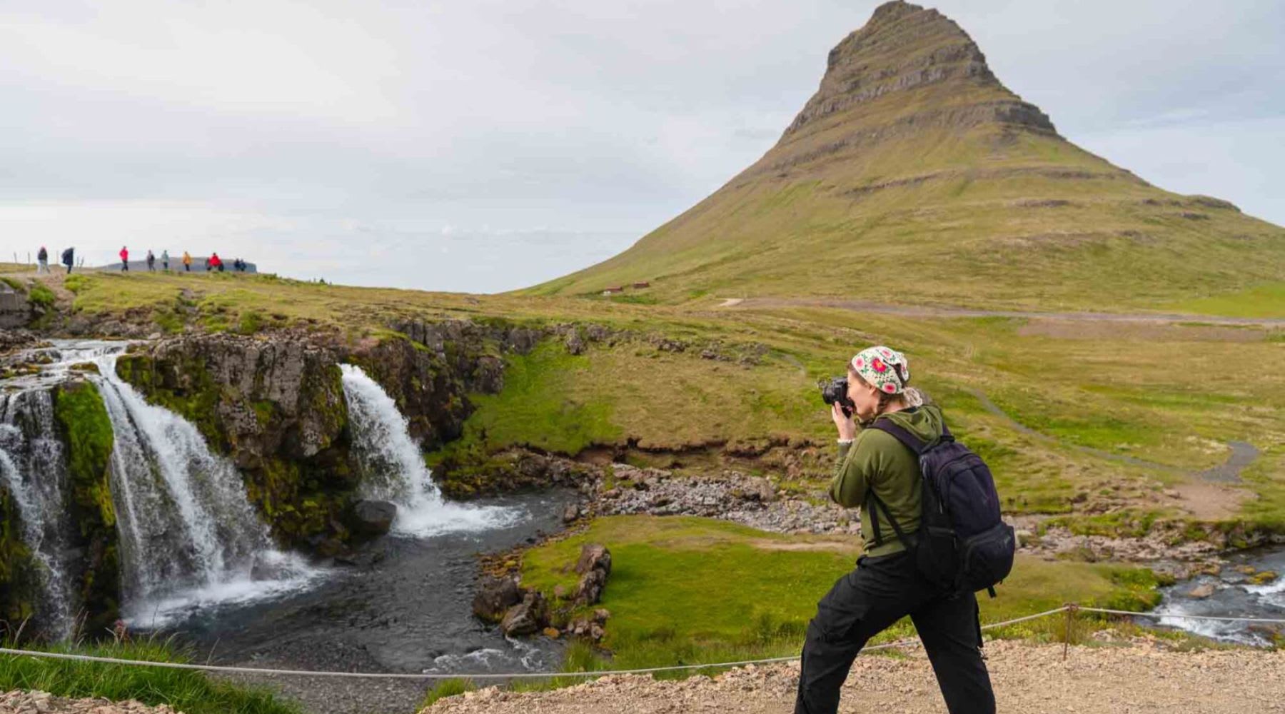 Turista che scatta foto alle cascate vicino alla montagna di Kirkjufell.