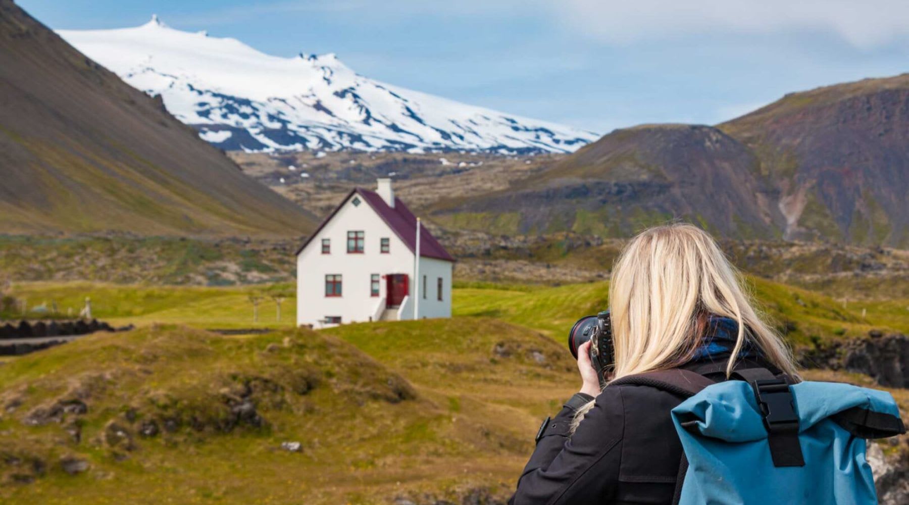 Turista bionda che scatta una foto delle fattorie vicino al vulcano Snæfellsjökull.