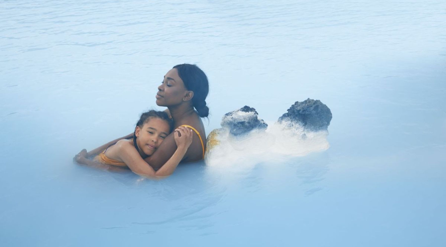 Woman and child relaxing in the milky blue geothermal waters of the Blue Lagoon