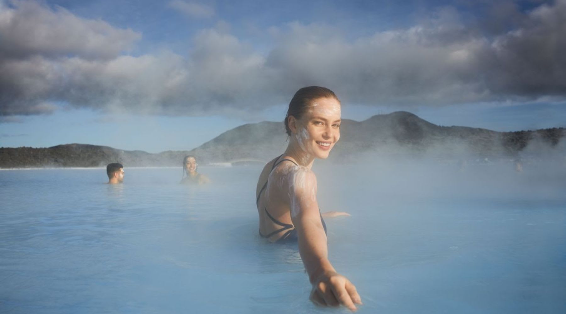 Woman smiling in the steamy blue waters of the Blue Lagoon with a silica mask on her face