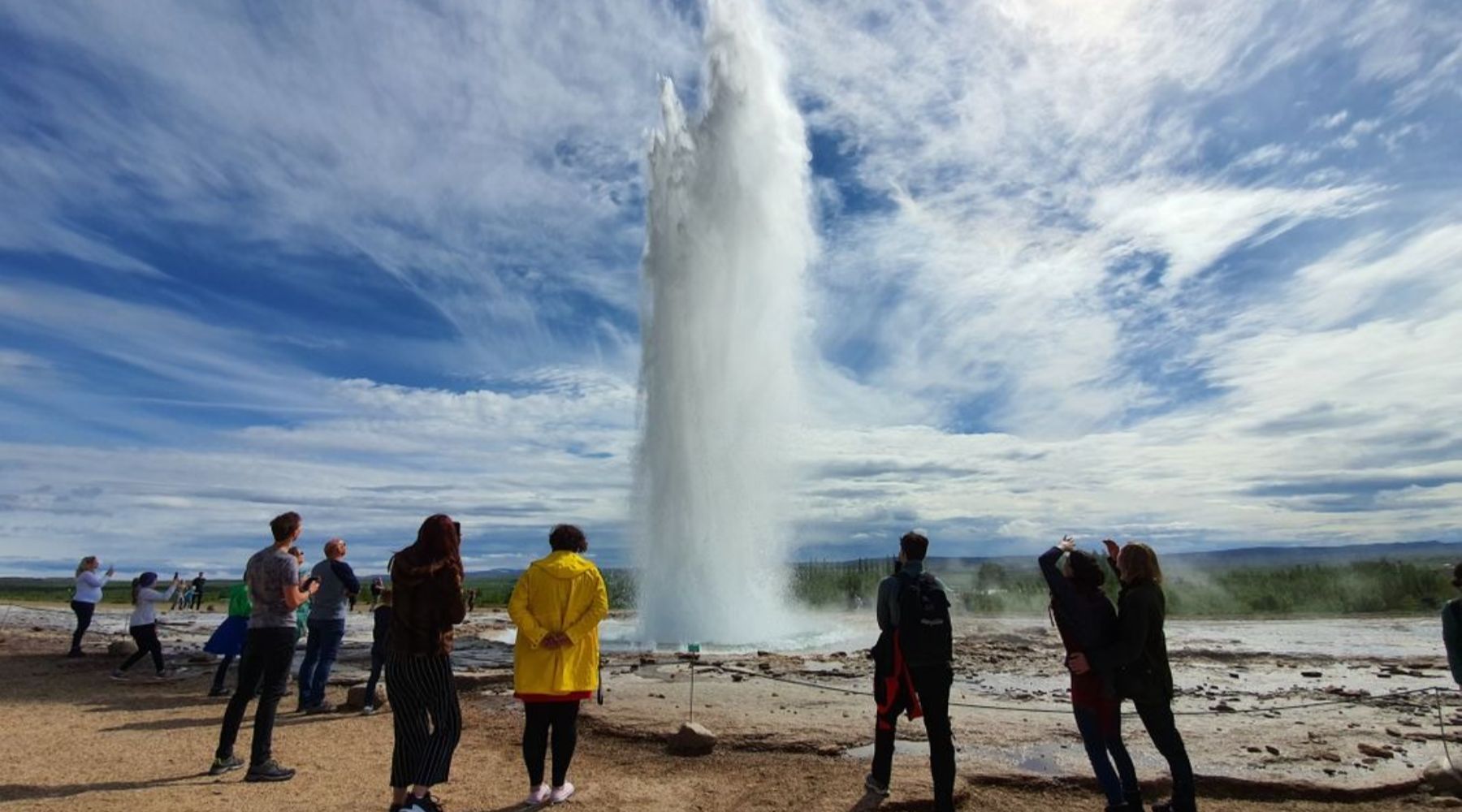 A group of tourists watching the Icelandic Geysir erupt.