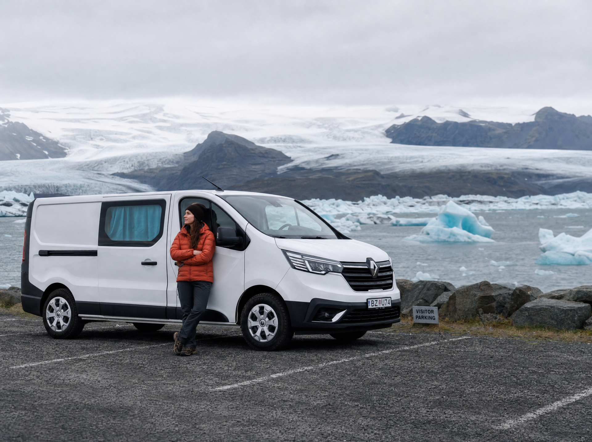 Autocamper parkeret ved siden af et vandfald omgivet af grønne bakker