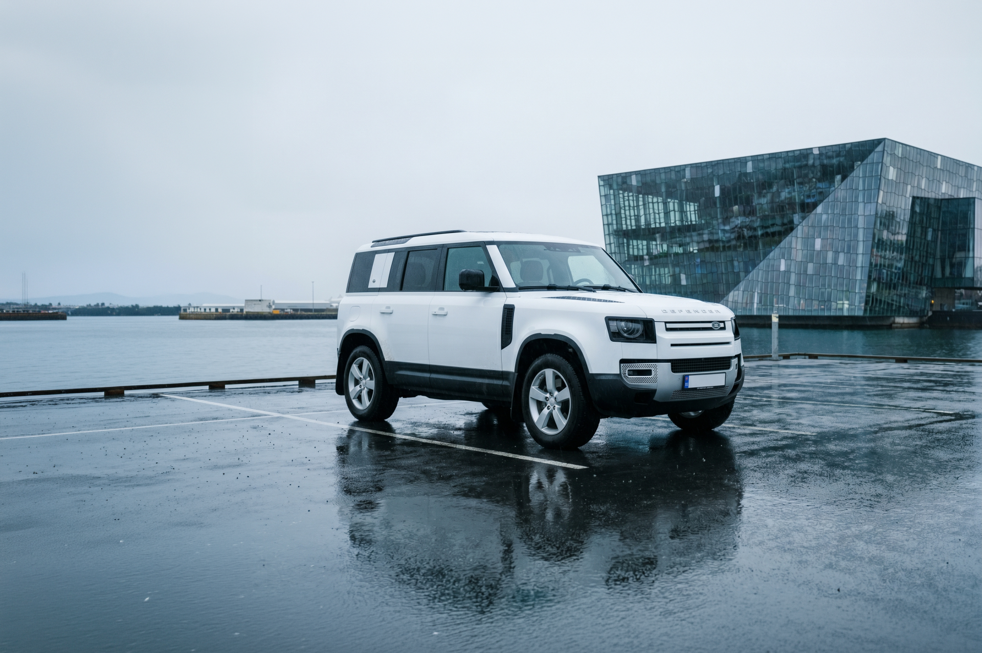 Hvid luksus-4x4-SUV parkeret ved siden af en rolig sø, der spejler himlen