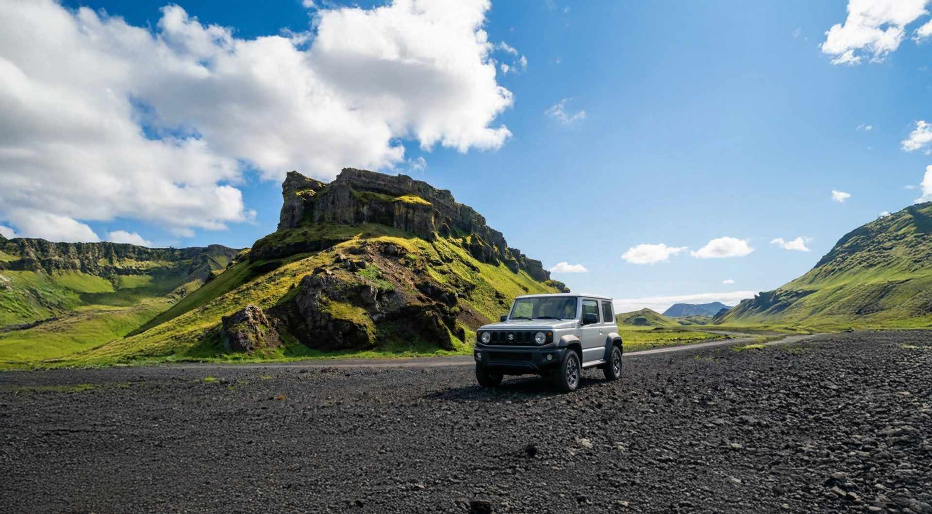 SUV blanco circulando por una carretera islandesa con montañas nevadas al fondo