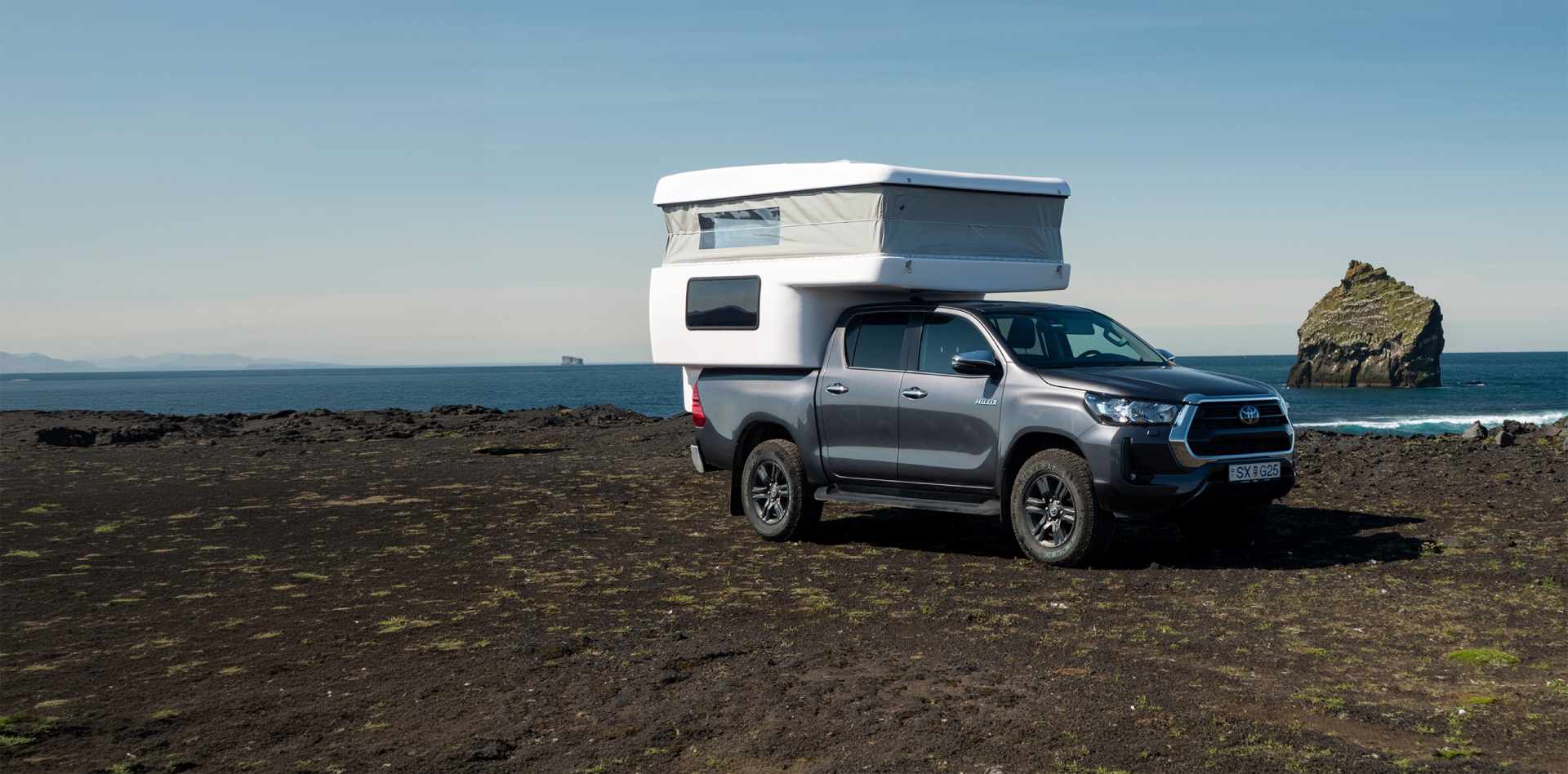 SUV blanco circulando por una carretera islandesa con montañas nevadas al fondo