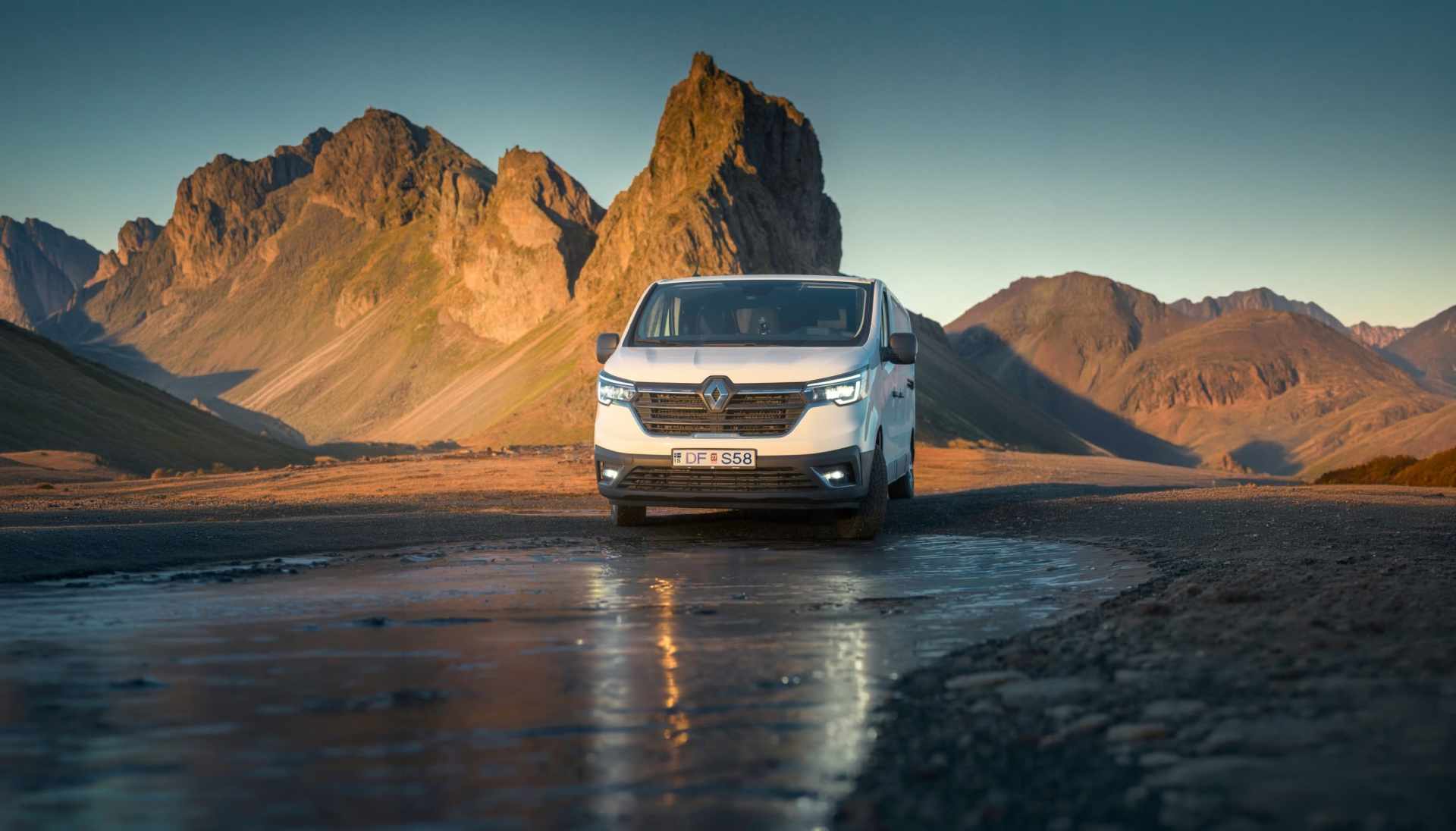 SUV blanco circulando por una carretera islandesa con montañas nevadas al fondo