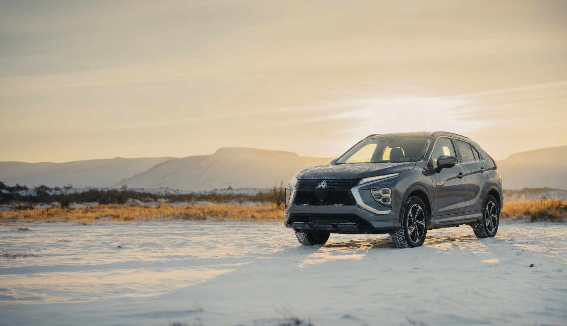 SUV blanco circulando por una carretera islandesa con montañas nevadas al fondo