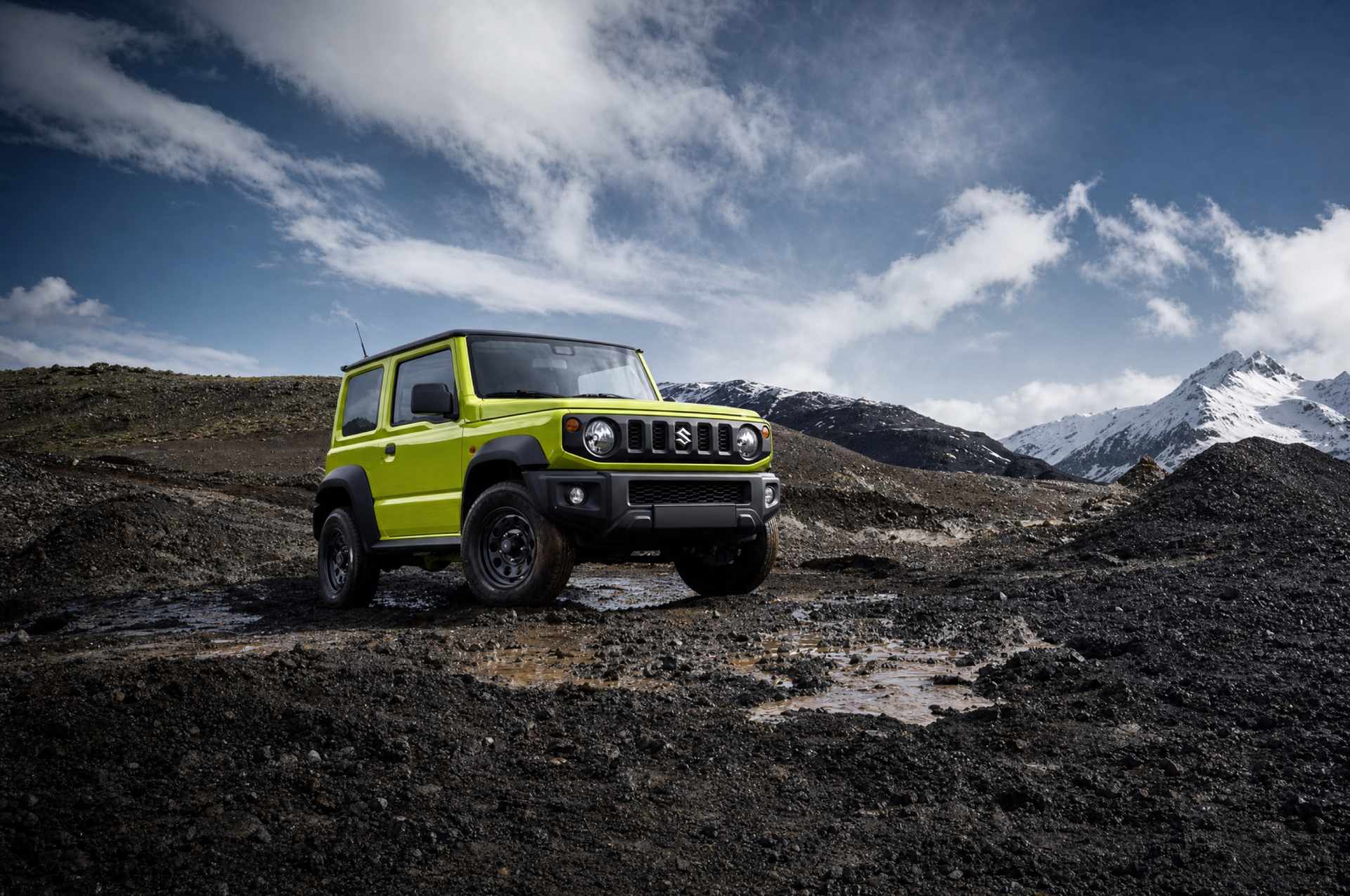 SUV blanco circulando por una carretera islandesa con montañas nevadas al fondo