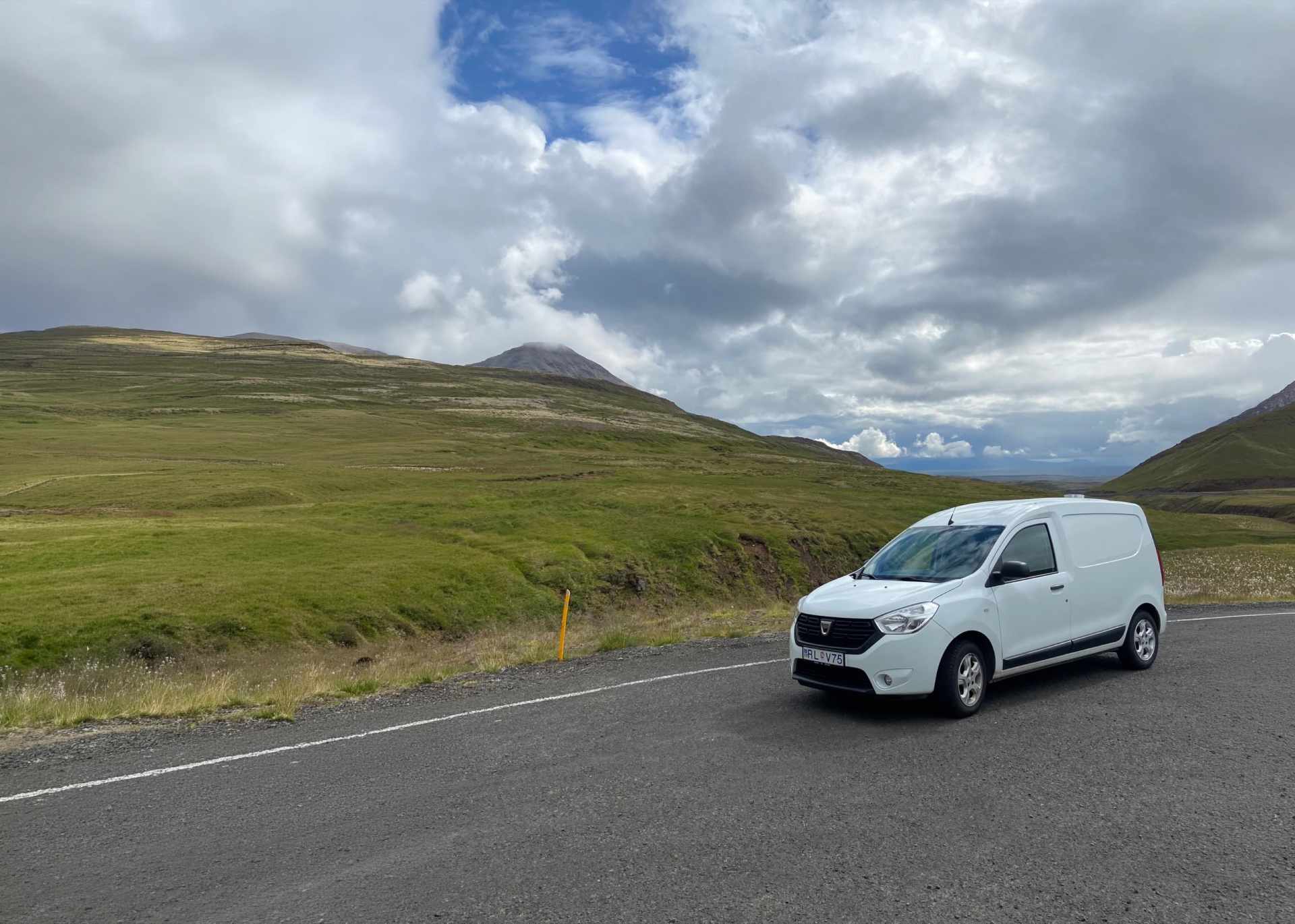 SUV blanco circulando por una carretera islandesa con montañas nevadas al fondo