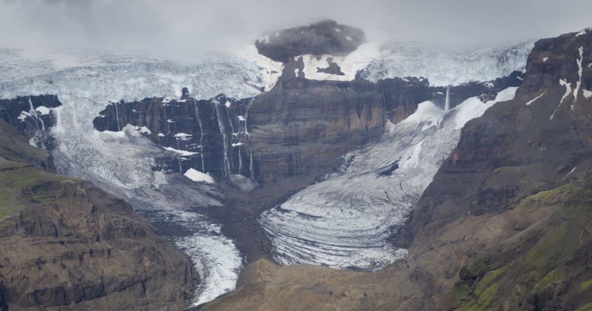 Morsárfoss waterfall plunging from Vatnajökull glacier cliffs in Iceland, with icefields, misty clouds and rugged mountain canyon