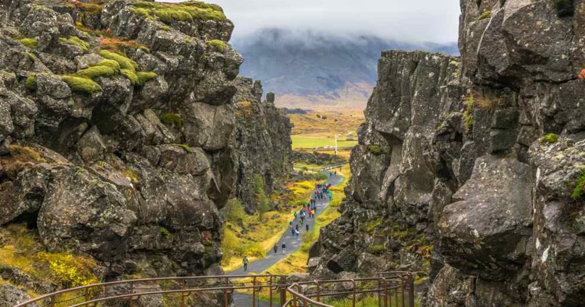 Visitors walking through Almannagjá gorge between moss-covered lava cliffs in Thingvellir National Park, Iceland’s dramatic rift valley