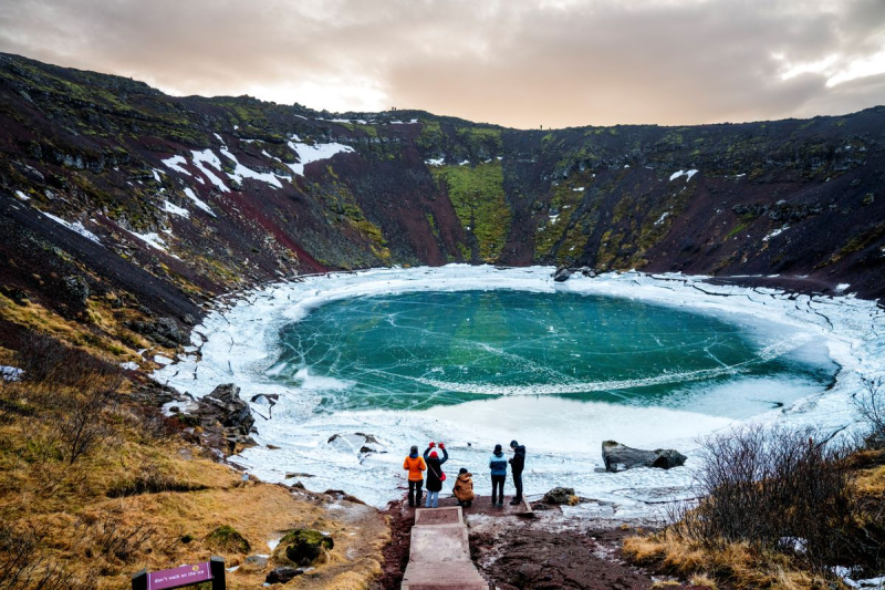 Snow-covered Kerið volcanic crater with a turquoise lake at the bottom