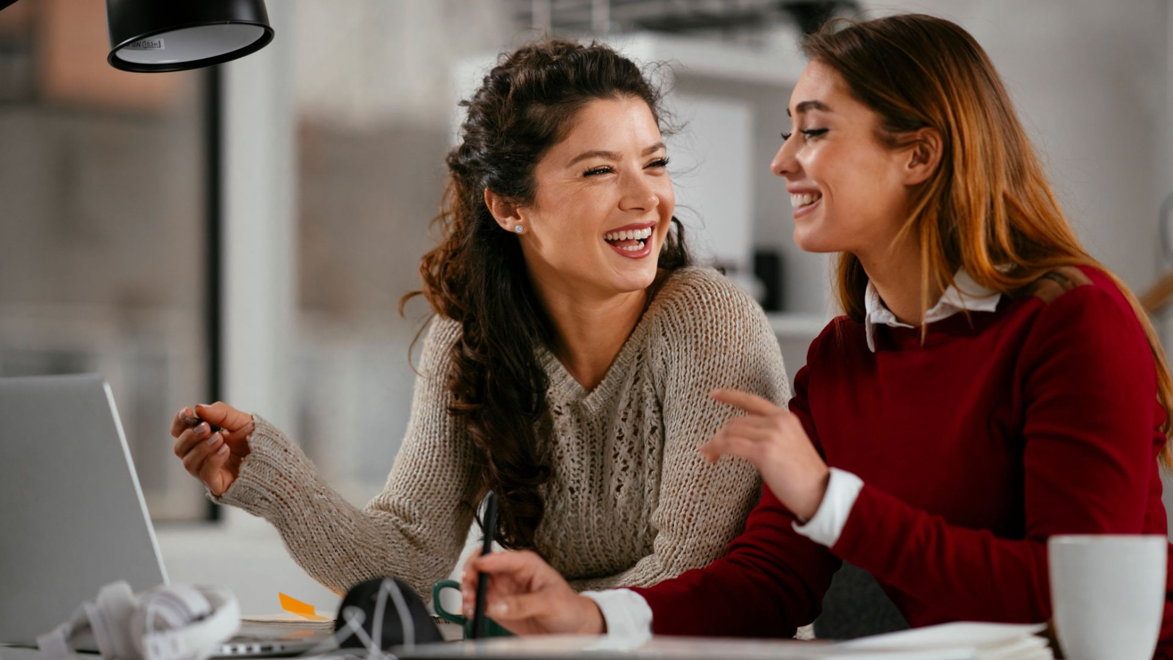 Two work best friends looking at each other and laughing