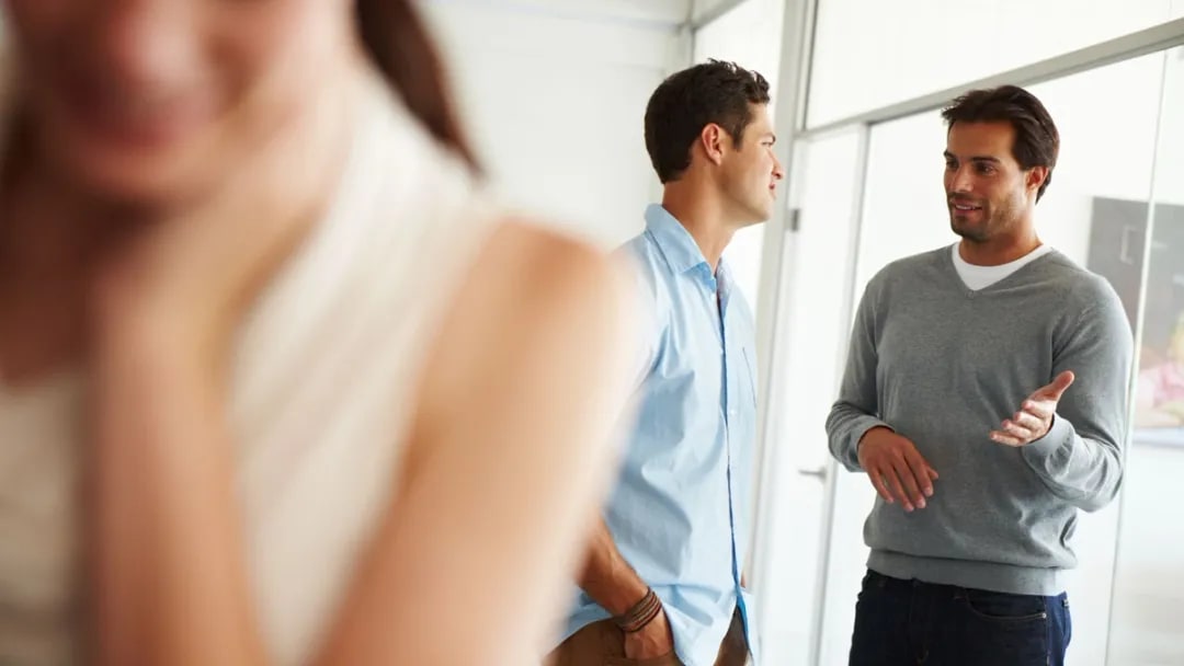 Two colleagues talking with a blurred person in the foreground