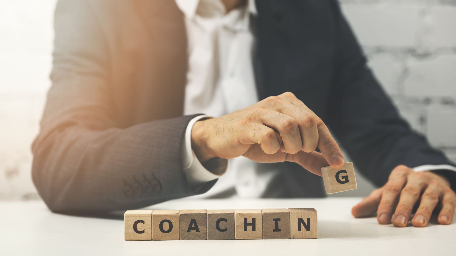 A visual representation of a coaching showing a person spelling out the word coaching with wooden blocks