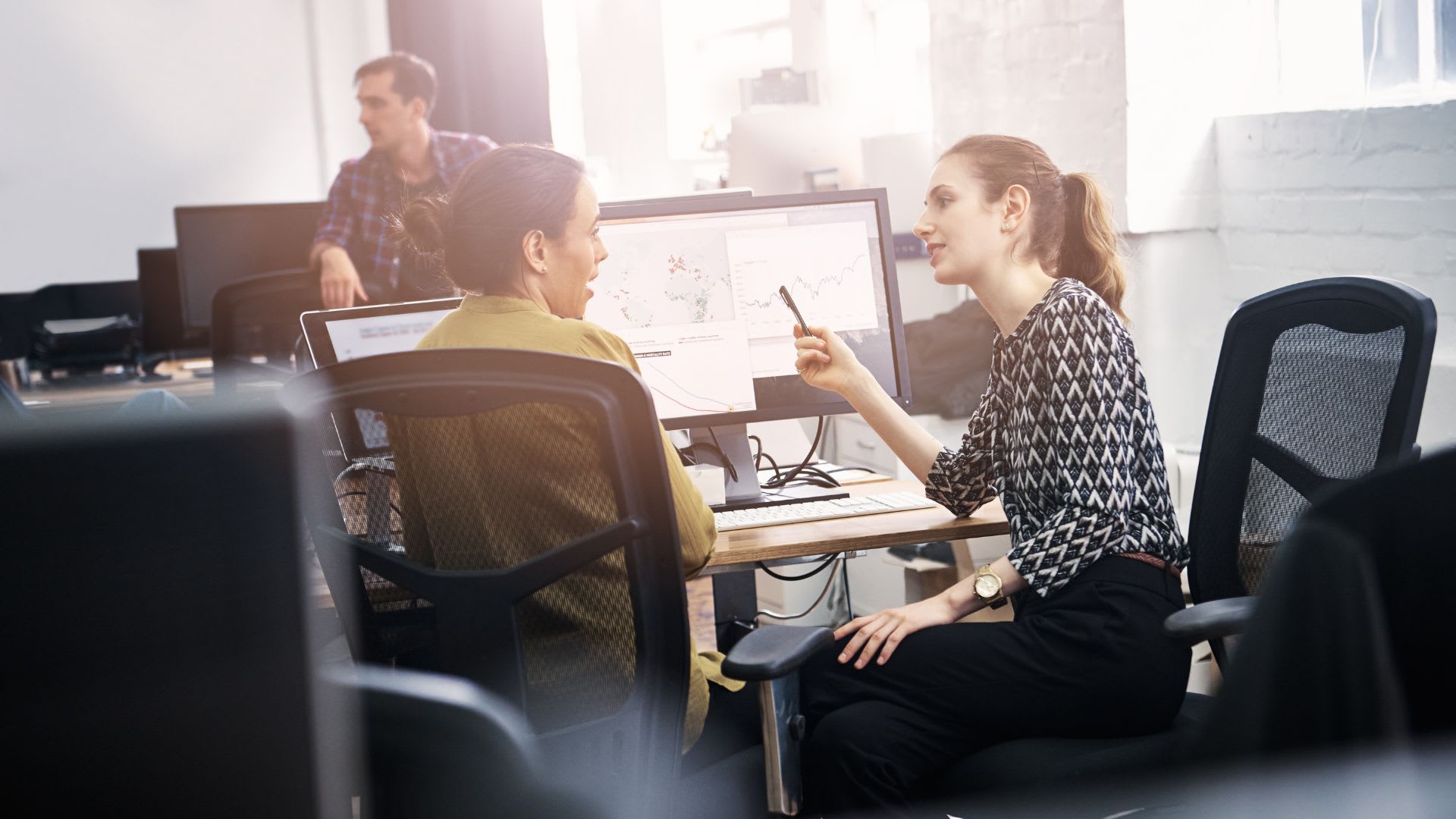 Two individuals engaged in a conversation while sitting at a desk, communicating 